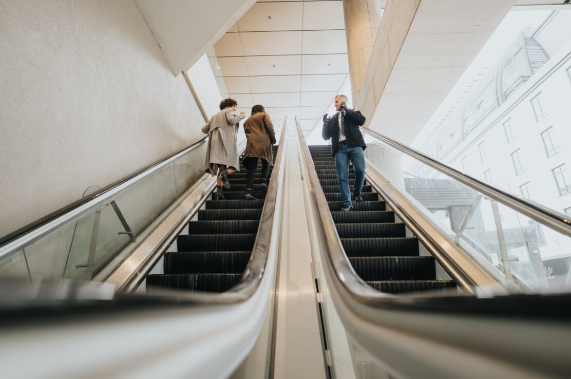 People using escalators in an office building.