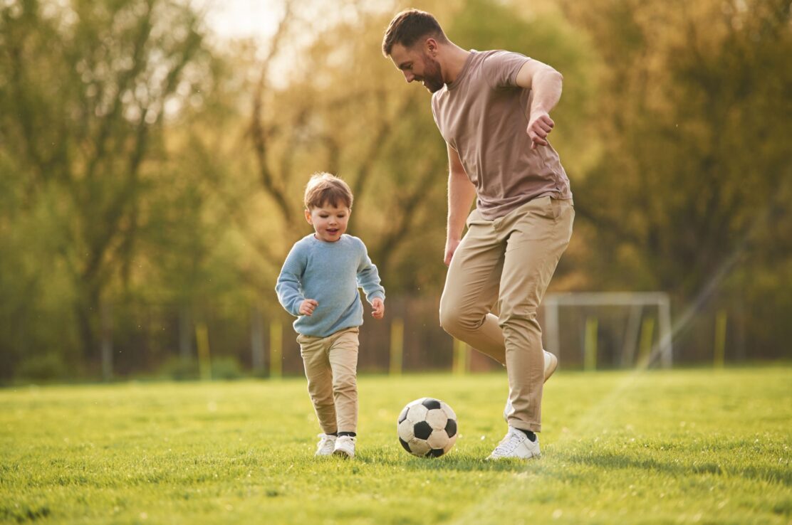 A father playing football with his young son.