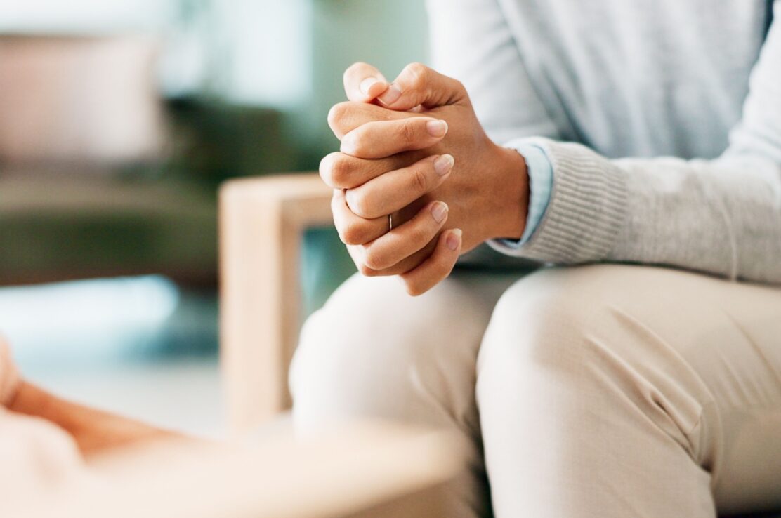 A woman sitting with her hands clasped.