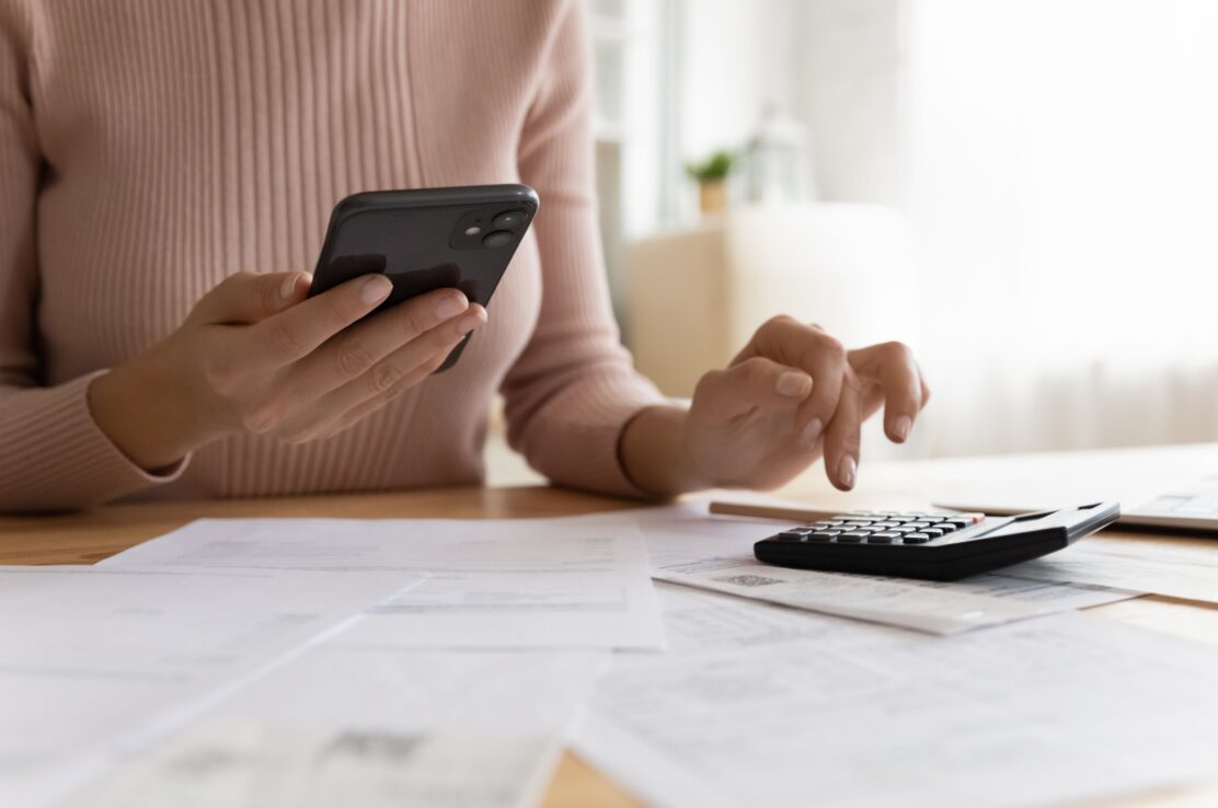 A woman using a phone and calculator