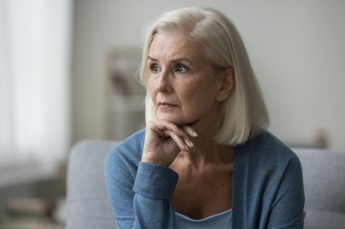 An older woman looks pensively off to one side.