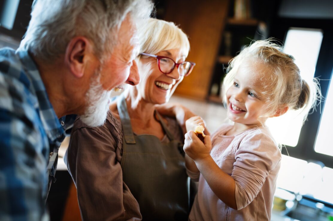 Happy smiling grandparents enjoying time with grandchild at home