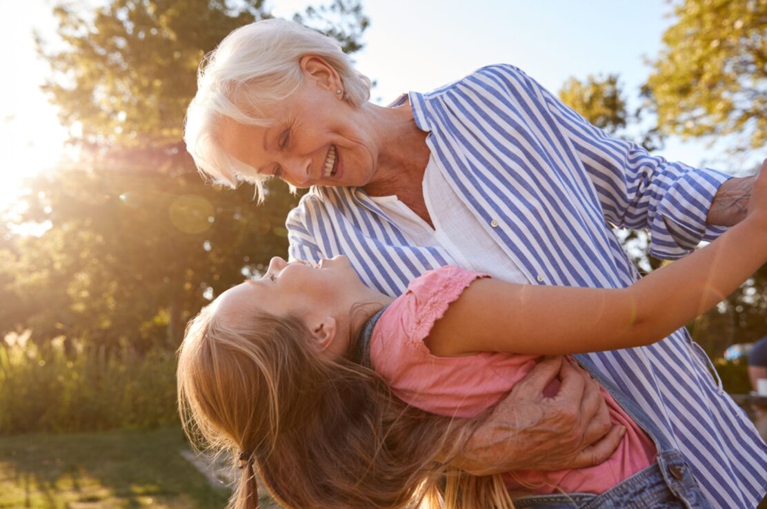 A grandmother playing with her granddaughter outside.